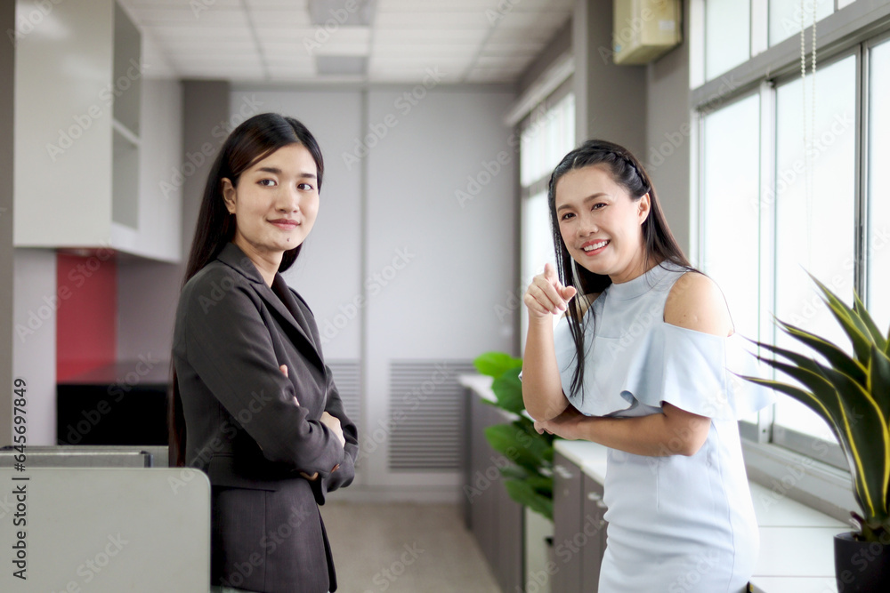 Two happy beautiful Asian women officers standing and talking during take break from work at office communicate with colleague coworker in company, female staff worker discussing together at workplace Two happy beautiful Asian women officers standing and talking during take break from work at office communicate with colleague coworker in company, female staff worker discussing together at workplace