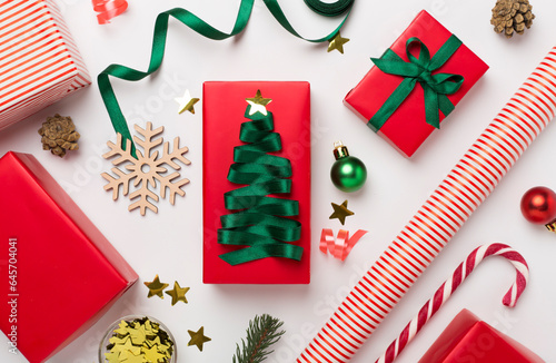 Gift boxes with paper's rools and christmas decoration on color background, top view