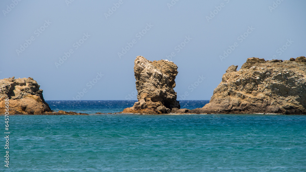 Tranquil Coastline Scenery with Blue Ocean, Sandy Beach, and Rocky Cliff