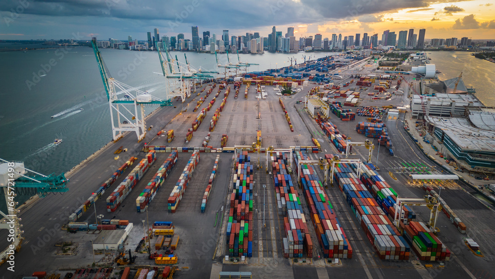 Naklejka premium Aerial at sunset of Miami Downtown skyline with port and crane logistic container cargo boat 