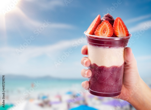 A bowl of açaí topped with strawberries on the beach.Acai bowl on tropical beach