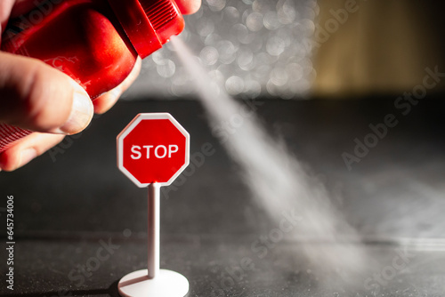 Using a red spray can with deodorant against a stop sign, environmental issue concept, soft focus photo