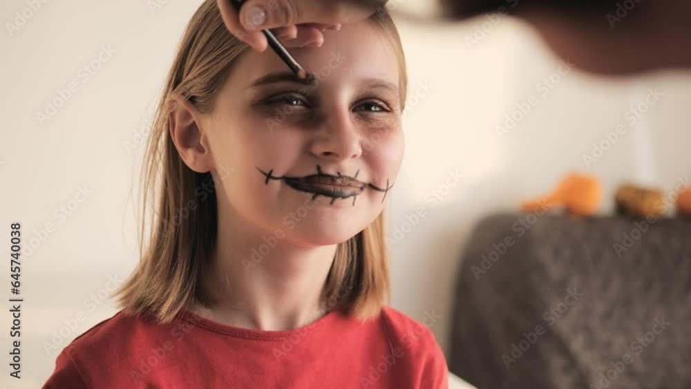 stockvideon-mother-making-halloween-makeup-to-preteen-girl-daughter-and