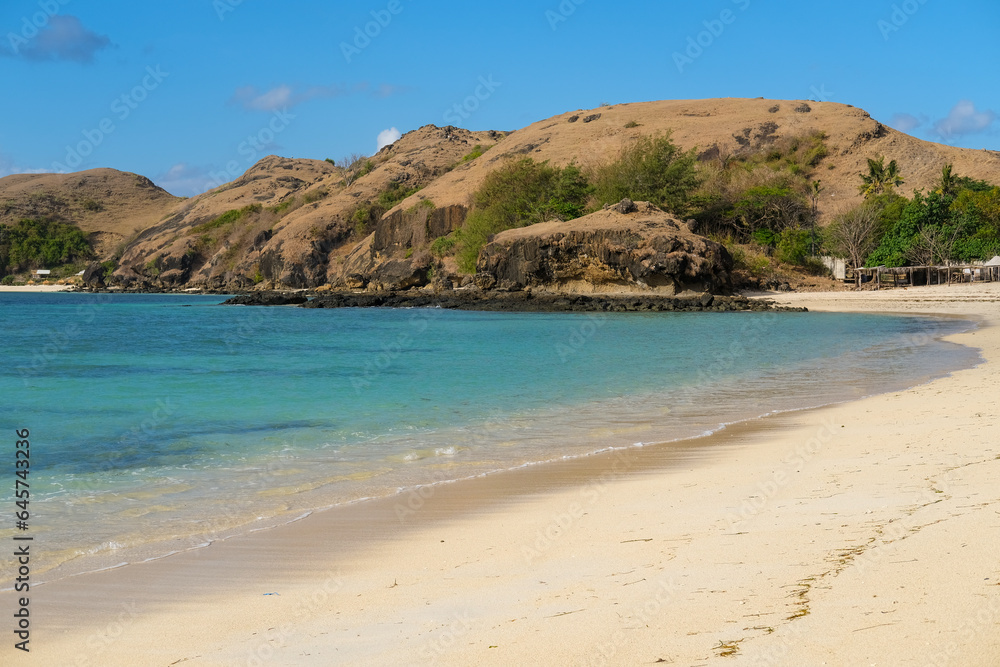 Kuta beach Lombok. Kuta Lombok is a small spread-out town in a beautiful bay lined by a long white sand beach, a beach with blue sky, a beach with sky and white sand, view of the beach in island