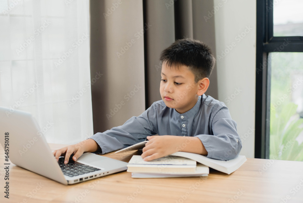 Little Asian boy student using computer laptop learning. Educational concept Social distancing, staying at home, presenting a modern educational way of life. Little Asian boy student using computer laptop learning. Educational concept Social distancing, staying at home, presenting a modern educational way of life.