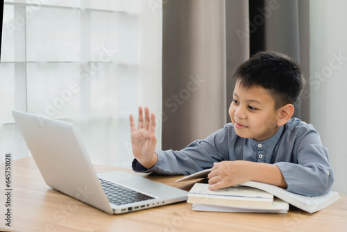 Little Asian boy student using computer laptop learning. Educational concept Social distancing, staying at home, presenting a modern educational way of life.