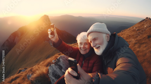 Senior tourist couple man and woman hiking and taking selfie at top beautiful mountains, sunset light