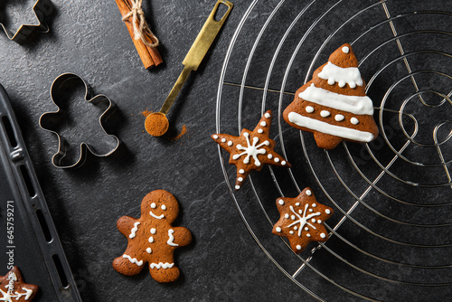 baking, cooking, christmas and food concept - close up of iced gingerbread cookies, molds, flour and oven tray on black table top at kitchen
