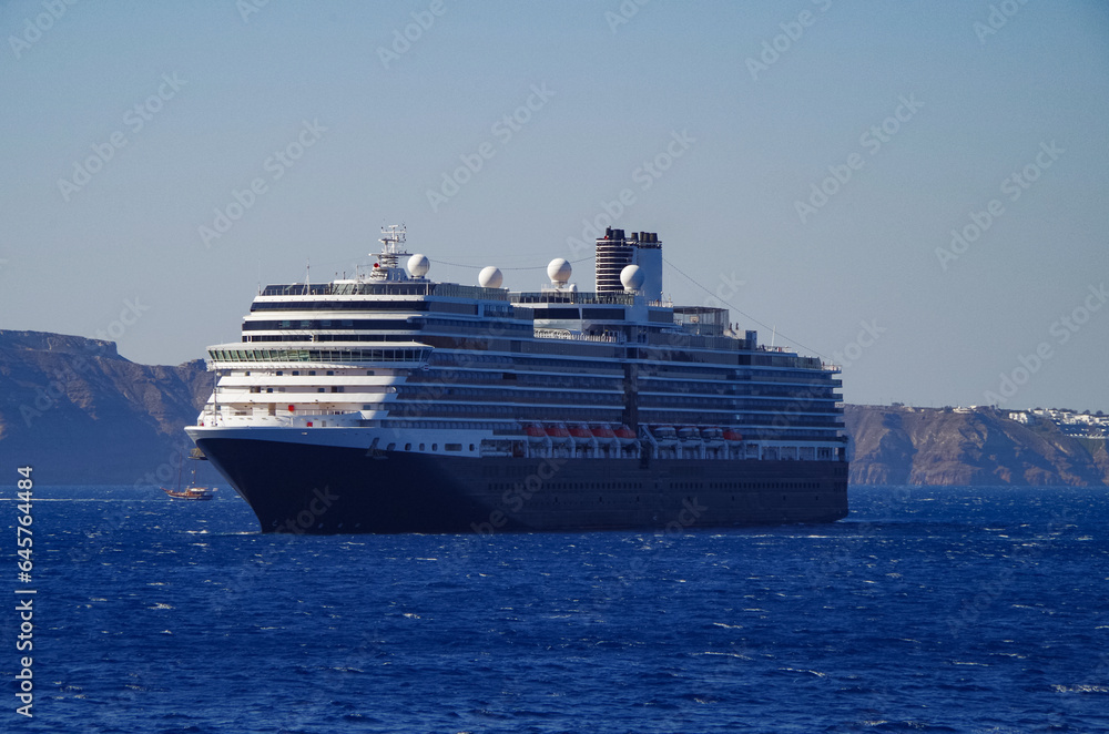 Luxury cruiseship cruise ship liner Eurodam anchoring at sea on sunny summer day during Mediterranean Greek Island cruise with shore and rocky island in background
