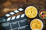 clapper board of video cinema in studio and bowls of different chips and candies on wooden table