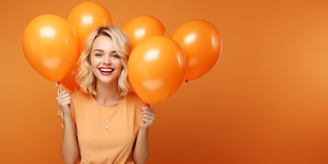 Beauty joyful teenage girl with orange yellow air balloons smiling on orange background with copy space, Thanksgiving celebration concept backgrounds.