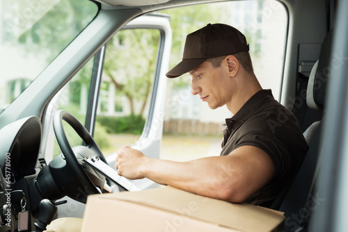 Delivery Man Checking List In Van