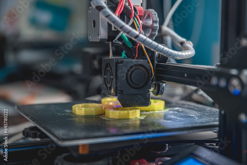 3D printer prints a model made of yellow plastic © iloli