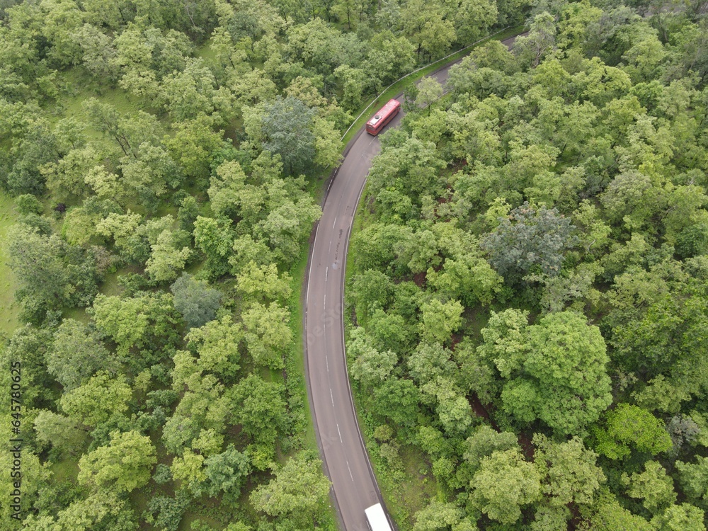 curvy highway road in the forest red bus india