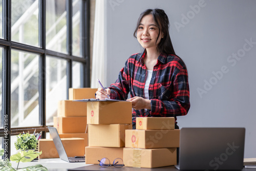 Startup happy Asian woman sme business owner work with prepare parcel delivery boxs at home, SME supply chain, procurement, package box to deliver to customers, Online SME business entrepreneurs ideas © David