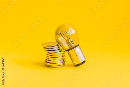 A lamp and money on a yellow background with copy space. Price for electricity concept. Expensive electricity cost.