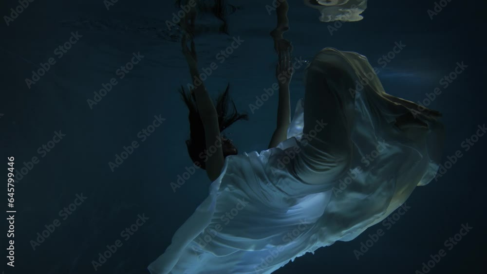 Slow motion plunging girl to fall under water. Girl swimming under water in basin. Woman dives in the pool.