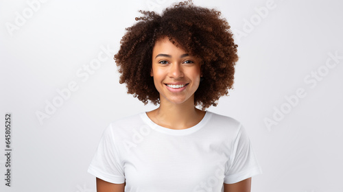 Young woman wearing white short sleeve top, a teenage, African girl smiling and standing against white background, studio shot.