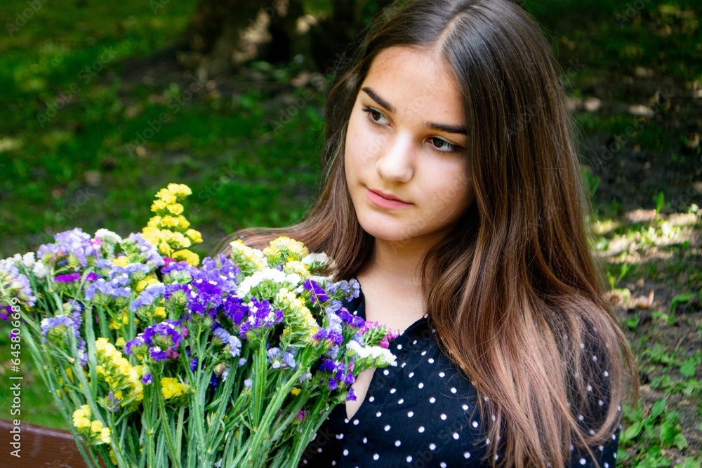 Emotional girl teenager with long hair hairstyle braids in a green shirt sits on a bench in the park. High quality photo Emotional girl teenager with long hair hairstyle braids in a green shirt sits on a bench in the park. High quality photo