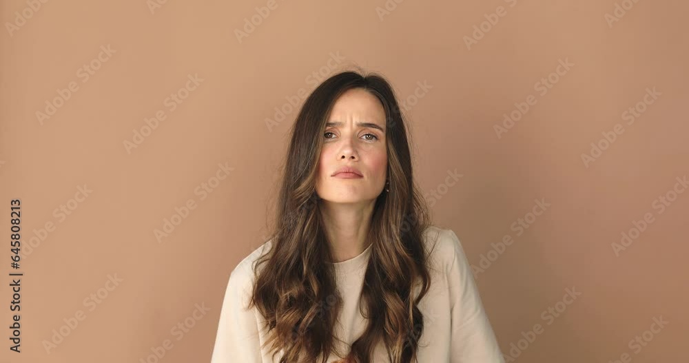 Doubtful woman looks with suspicion. Spy and curiosity concept. Curious, suspicious, looks with disbelief at camera isolated on beige background. Girl not sure, shrugging shoulders, not know. Doubtful woman looks with suspicion. Spy and curiosity concept. Curious, suspicious, looks with disbelief at camera isolated on beige background. Girl not sure, shrugging shoulders, not know.