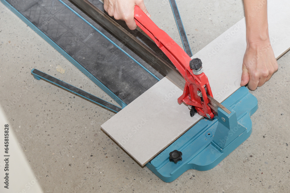 Cutingt tiles with a standard manual tile cutter. Process of installation of tiles in the bathroom step by step. DIY home improvement. 
