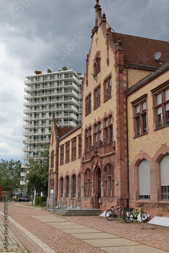 Ehemalige Zollhalle in Freiburg-Brühl mit modernen, nachhaltigen Hochhaus im Hintergrund