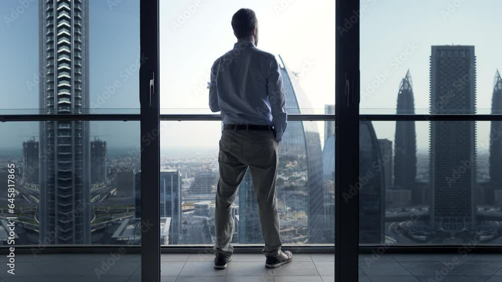 Young Man Succeed In High Rise Apartment Looking at Urban Buildings Young Man Succeed In High Rise Apartment Looking at Urban Buildings