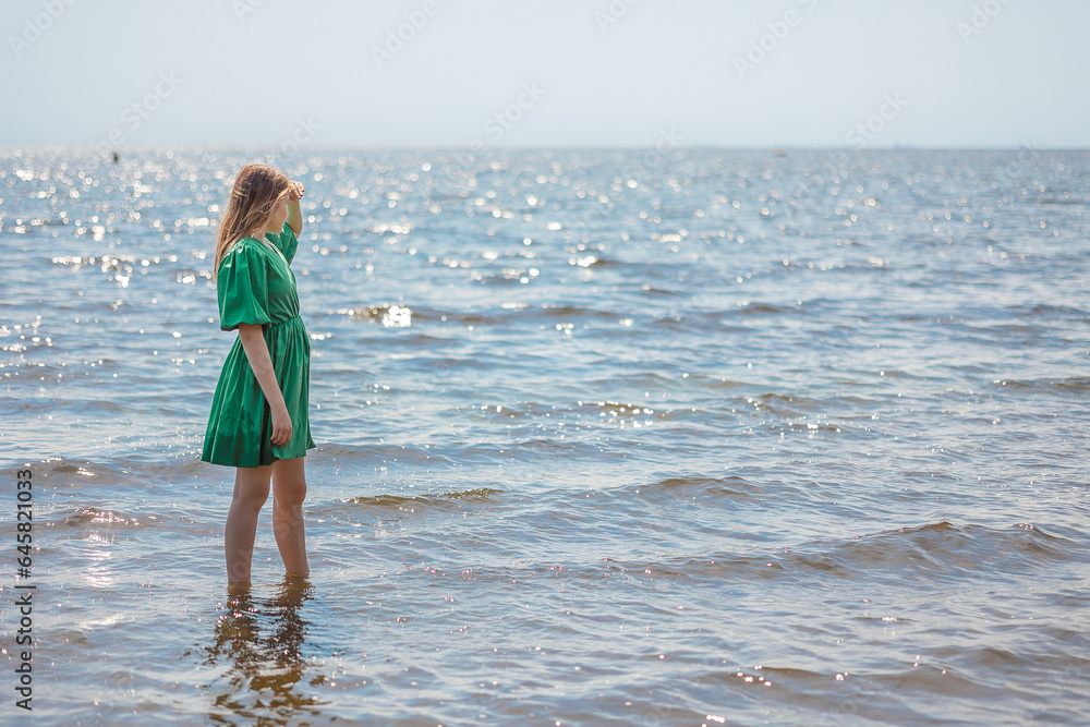 Beautiful young blonde girl looking at calm sea and blue sky. Side view. High quality photo Beautiful young blonde girl looking at calm sea and blue sky. Side view. High quality photo