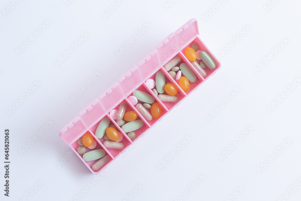 Close-up of a pink pill organiser with medicine inside.