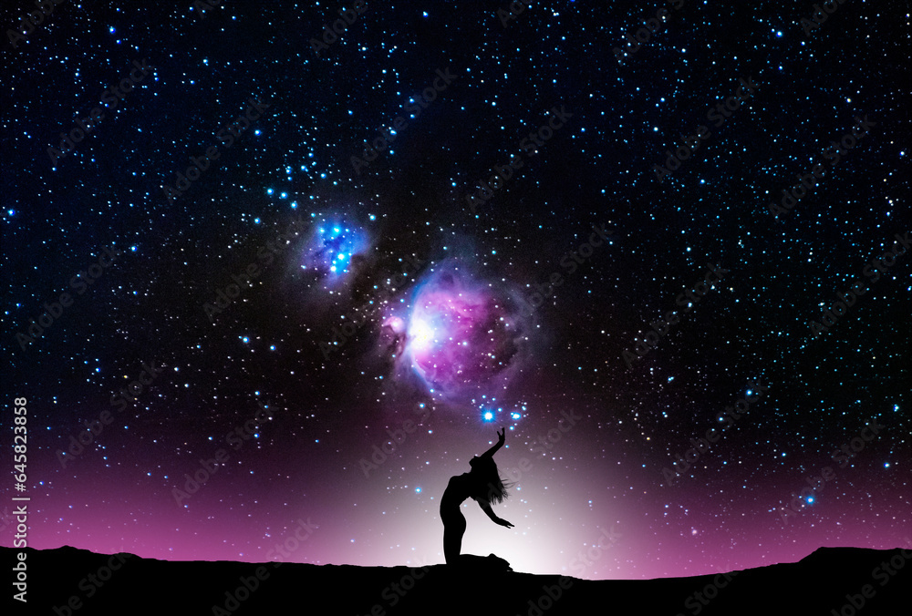 Woman silhouette dancing in the night, on the bright Orion Galaxy background.