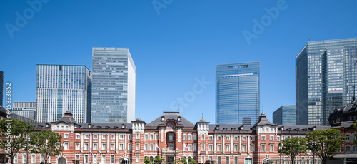 exterior view of Tokyo station from above he tracks in Tokyo, Japan on a sunny and partly cloudy day with skyscrapers in the background along with the Tokyo skyline