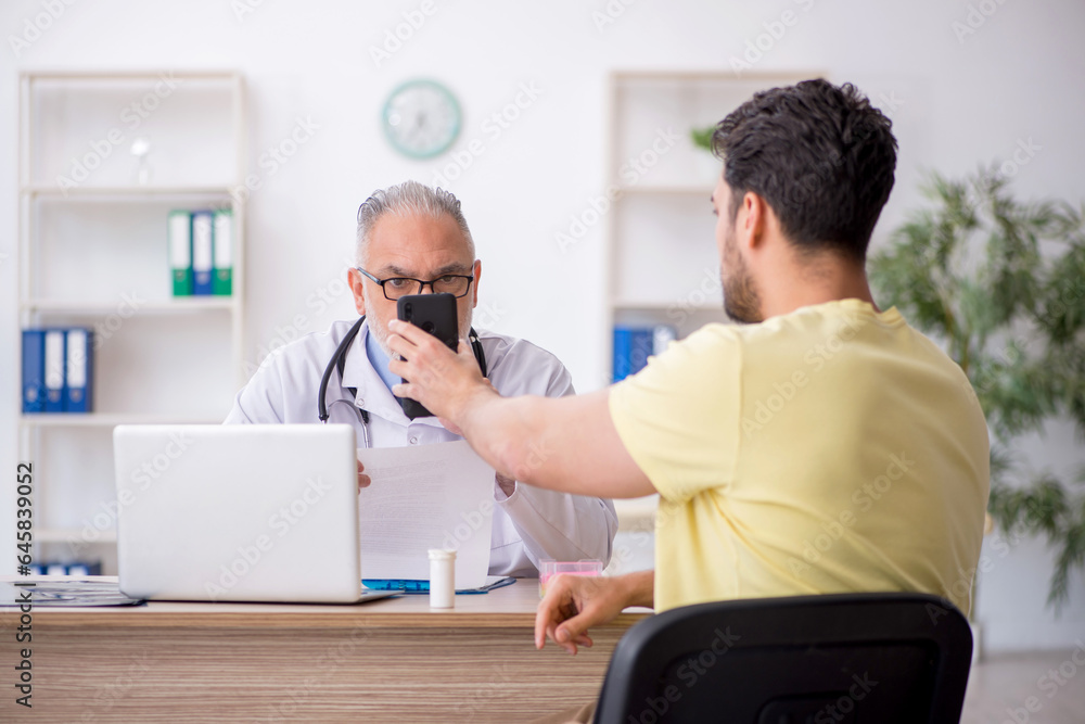 Young male patient visiting old male doctor Young male patient visiting old male doctor