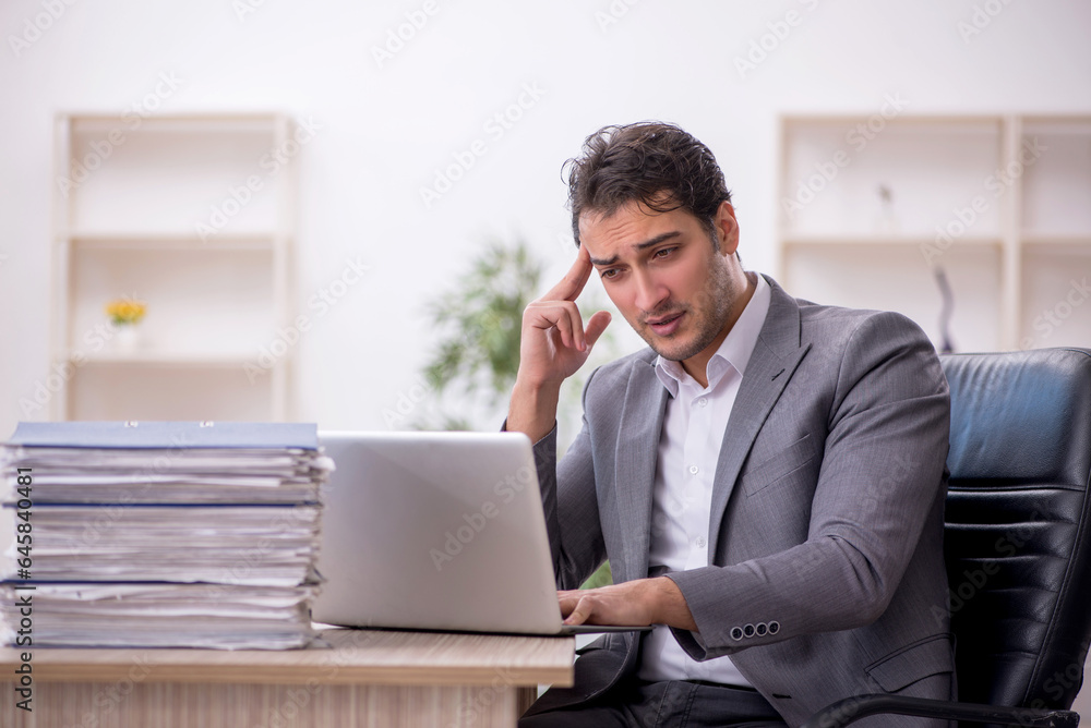 Young male employee and too much work in the office Young male employee and too much work in the office