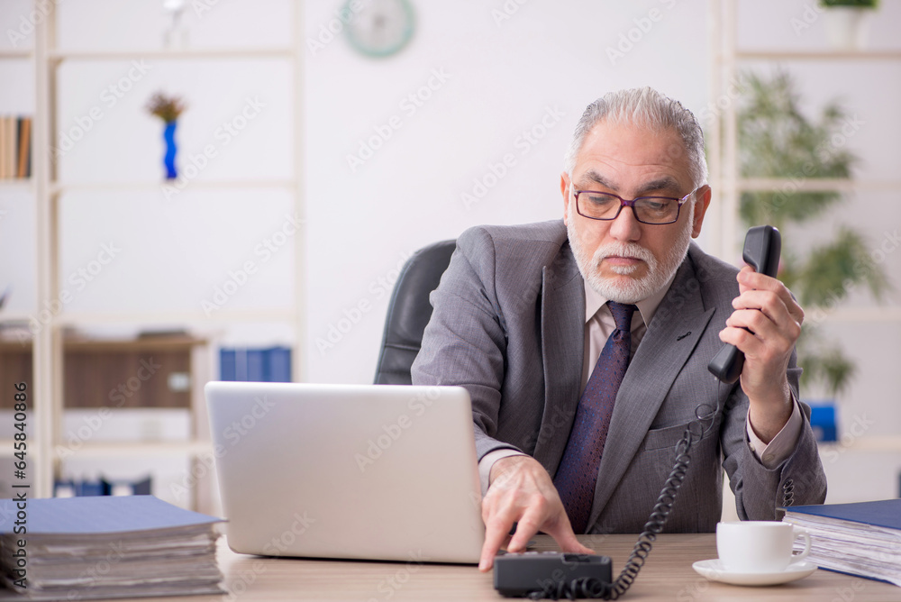 Old male employee working in the office Old male employee working in the office
