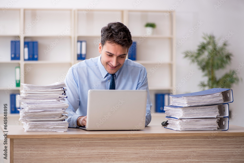 Young male employee and too much work in the office Young male employee and too much work in the office