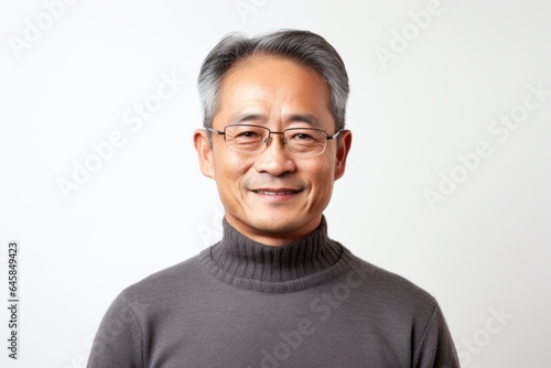Portrait photography of a Vietnamese man in his 50s wearing a cozy sweater against a white background © Anne Schaum