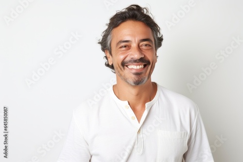 Portrait photography of a Colombian man in his 40s wearing a simple tunic against a white background