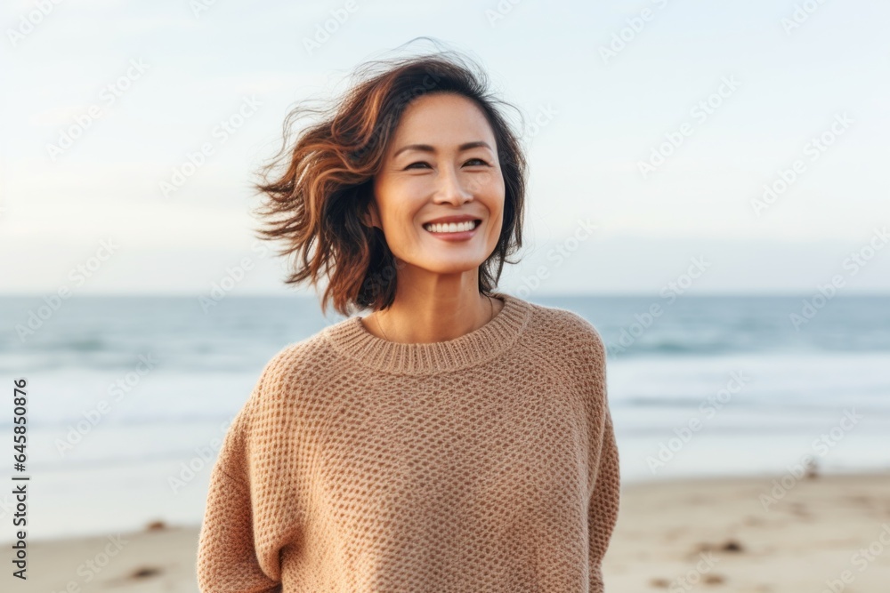 Portrait photography of a Vietnamese woman in her 40s wearing a cozy sweater against a beach background Portrait photography of a Vietnamese woman in her 40s wearing a cozy sweater against a beach background