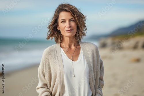 Lifestyle portrait photography of a serious French woman in her 40s against a beach background © Anne Schaum