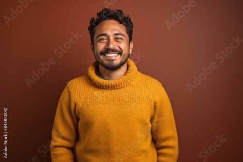 Portrait photography of a Peruvian man in his 30s wearing a cozy sweater against an abstract background