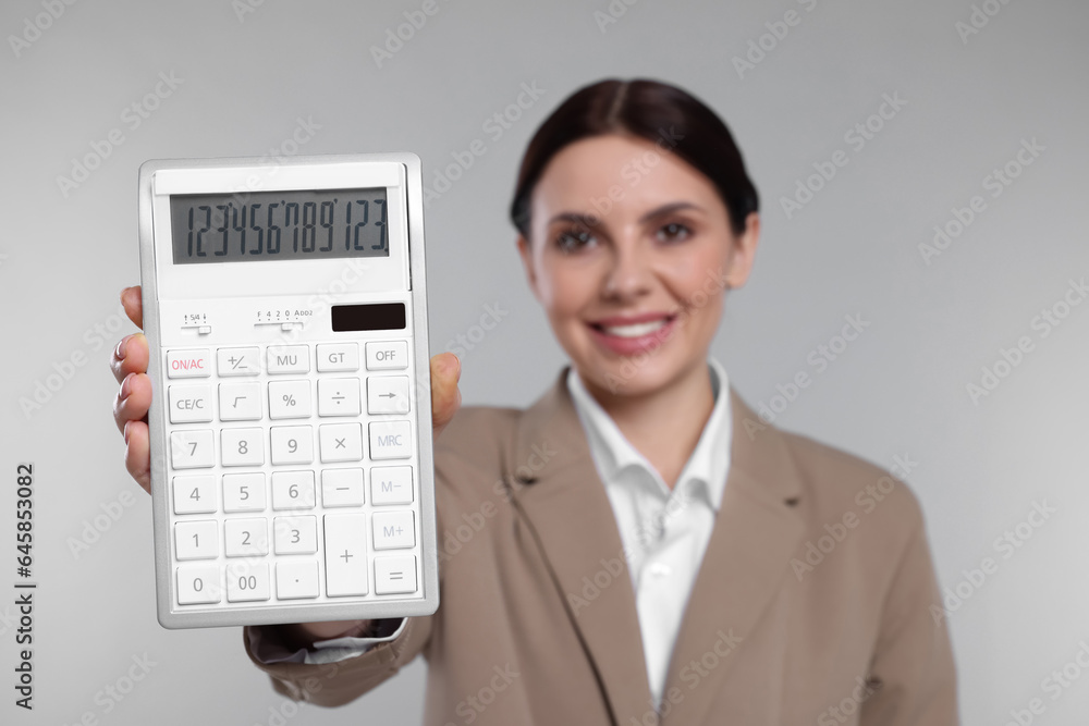 Smiling accountant against grey background, focus on calculator Smiling accountant against grey background, focus on calculator