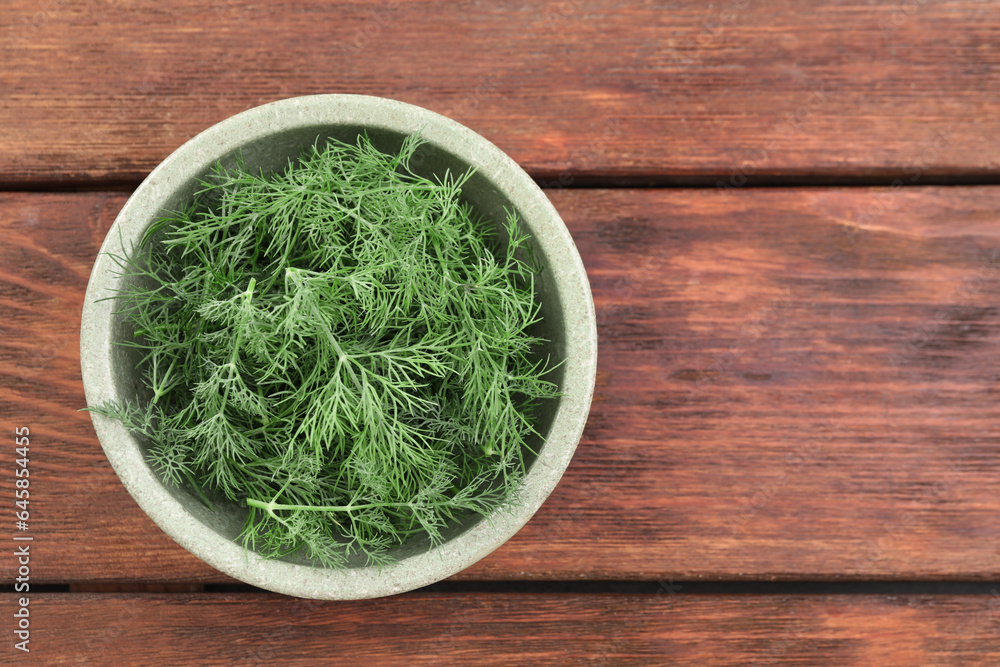 Bowl of fresh dill on wooden table, top view. Space for text Bowl of fresh dill on wooden table, top view. Space for text