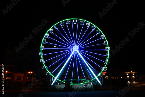Beautiful glowing Ferris wheel on city street at night © New Africa