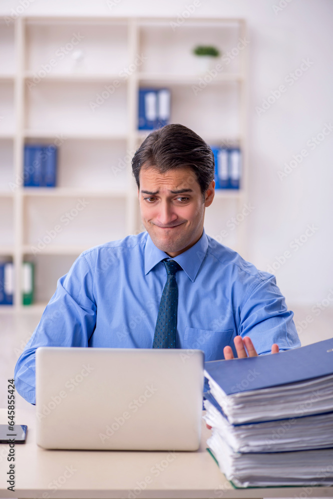 Young male employee and too much work in the office Young male employee and too much work in the office