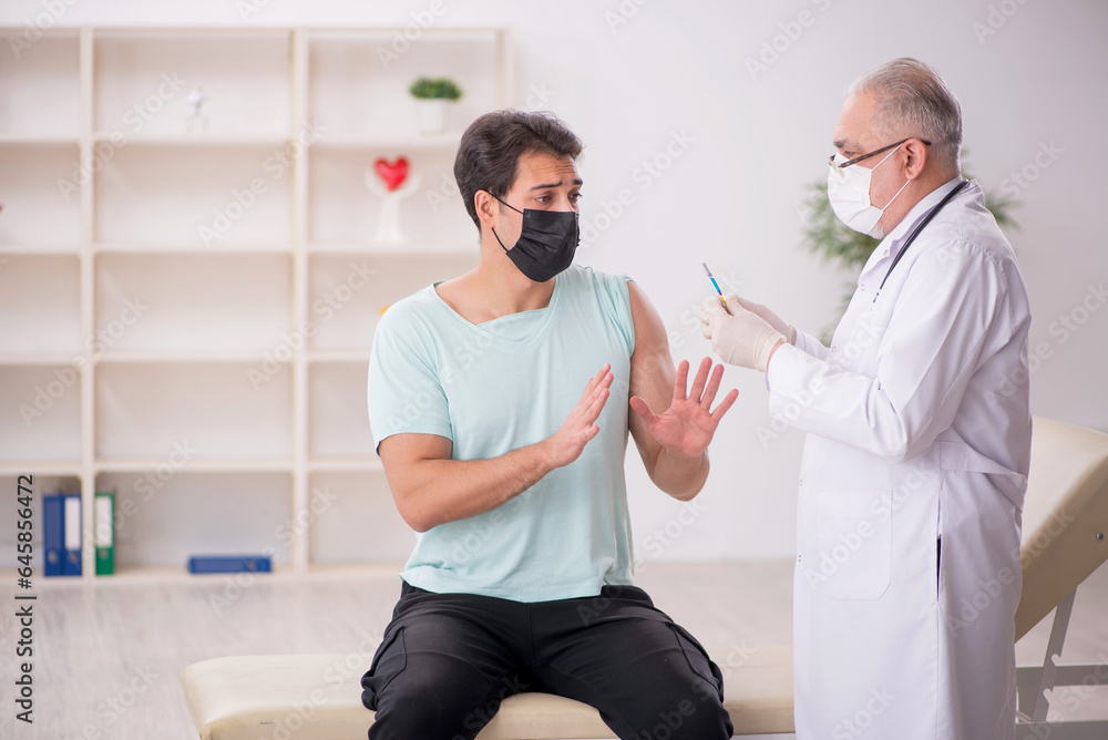 Obraz premium Young male patient visiting old male doctor in vaccination conce