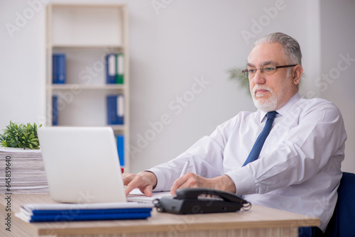 Old male employee working in the office