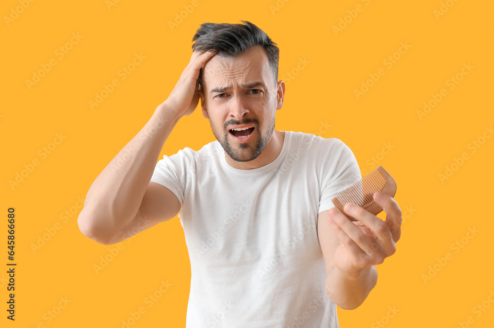 Worried young man with hair loss problem and comb on yellow background Worried young man with hair loss problem and comb on yellow background