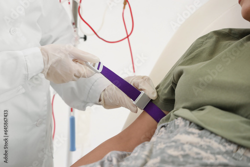 Doctor preparing female soldier for blood transfusion in clinic  closeup