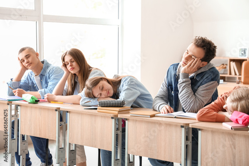 Tired sleepy classmates sit...