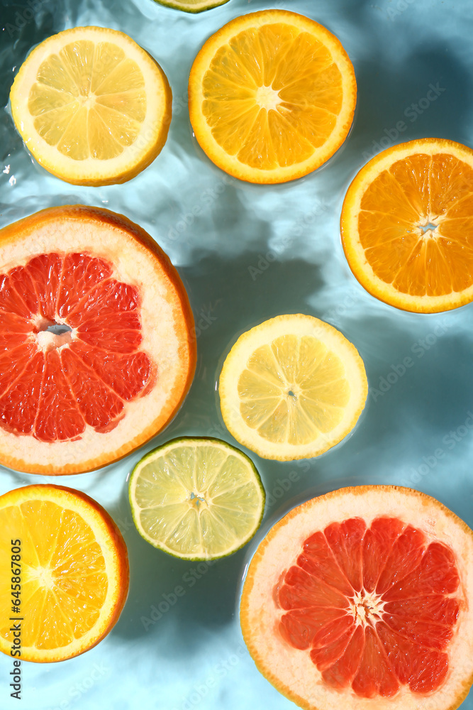 Different citrus fruit slices in water on blue background Different citrus fruit slices in water on blue background